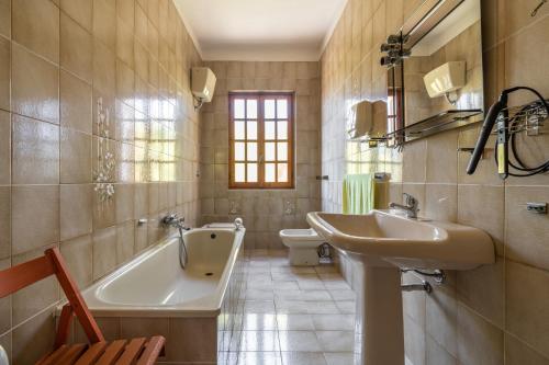 a bathroom with a sink and a tub and a toilet at Casa vacanza Elena in Sarroch