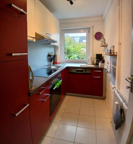 a small kitchen with red cabinets and a window at Apartment Flora in Stockach