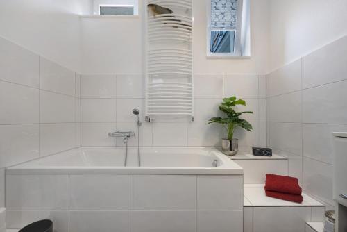a white bathroom with a tub and a plant at Wohnung Hildesheim in Hildesheim
