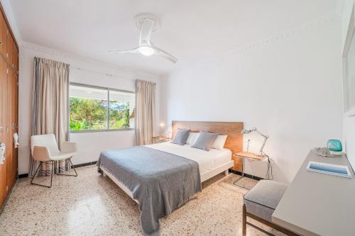 a white bedroom with a bed and a window at Villa Son Bibiloni in Algaida