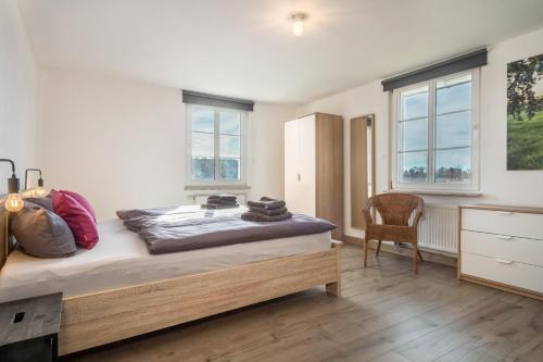 a bedroom with a bed and a chair and windows at Ferienwohnung am Hopfengarten in Tettnang