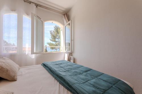a bedroom with a bed and two windows at Villa Alpaga Esterel Vue Mer in Saint-Raphaël