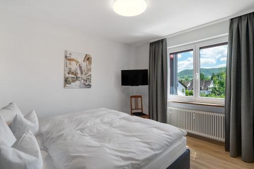 a bedroom with a white bed and a large window at Modern eingerichtetes Apartment in Achern