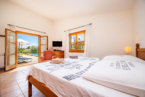 a white bedroom with a bed and a chair at Finca Can Xerpeta in Son Servera