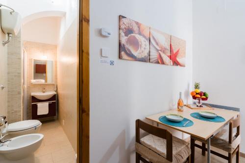 a bathroom with a toilet and a table with chairs at Kyma monolocale ad Otranto in Otranto