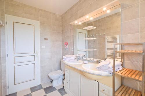 a bathroom with a sink and a toilet and a mirror at Le Perchoir Avec Piscine et Clim in Savignac-les-Églises