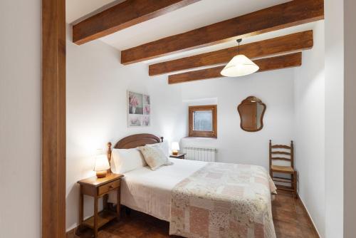 a bedroom with a white bed and wooden beams at Cal Colom - Agroturisme in Puigreig