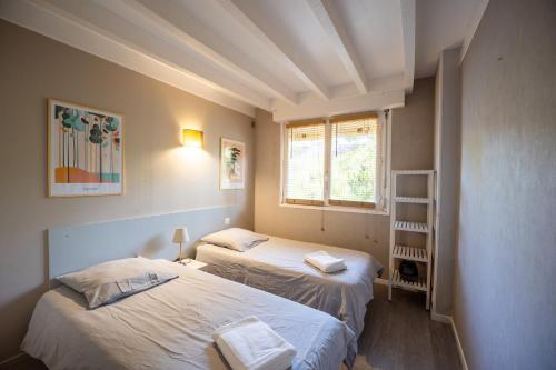 two beds in a small room with a window at Seignosse Le Penon, maison Patio in Seignosse