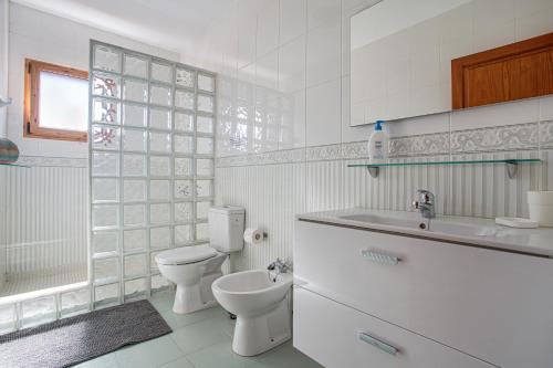 a white bathroom with a toilet and a sink at Villa Lea in Puerto del Carmen