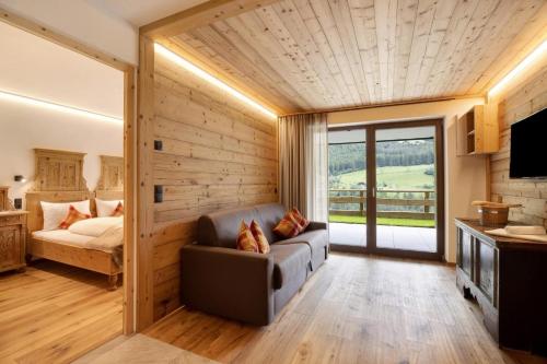 a room with a couch and a bed and a window at Archehof Hochzirm Lodge Anton in Campo Tures