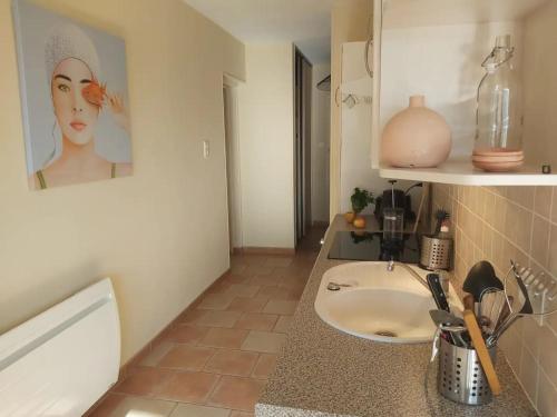 a bathroom with a sink with a picture of a woman at Superbe appartement avec loggia in Super Besse