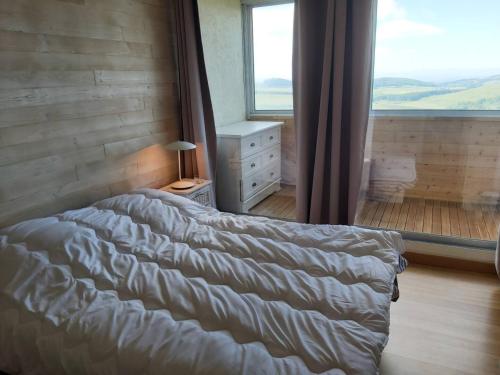 a bed in a bedroom with a large window at Superbe appartement avec loggia in Super Besse