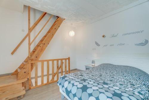 a bedroom with a bed and a wooden staircase at Maison proche Mont St Michel in Pontorson