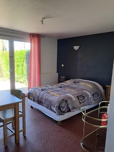 a bedroom with a bed and a table and a window at Le paradis de Marie in Treignac