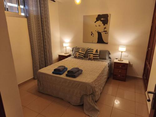 a bedroom with a bed with two lamps and towels on it at Ático Los Seres in Los Cristianos