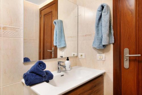 a bathroom with a sink with a mirror and blue towels at Ático Los Seres in Los Cristianos