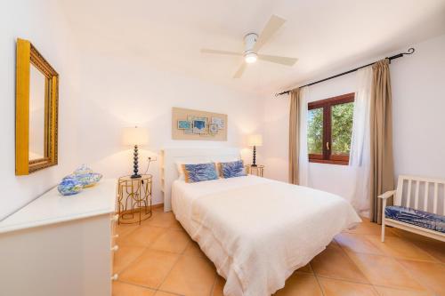 a white bedroom with a bed and a window at Villa Rico in Portocolom