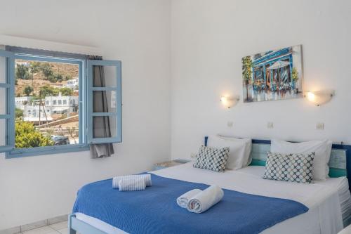 a bedroom with a large bed with blue sheets and a window at Pico Bello Patmos 18 in Patmos