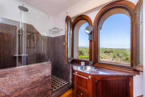 a bathroom with a sink and a shower and two windows at Villa Rico in Portocolom