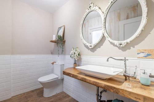 a bathroom with a sink and a toilet and mirrors at Can Tosca in Jávea