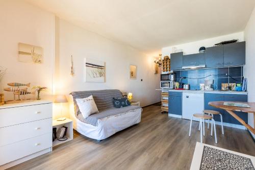 a living room with a couch and a kitchen at Studio Cosy face à l'océan in Lacanau