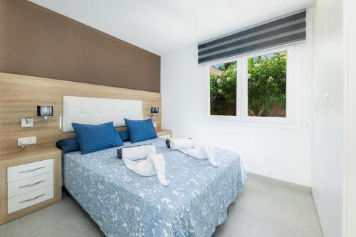 a bedroom with a bed with blue pillows and a window at Villa Neptuno in Cala Ratjada