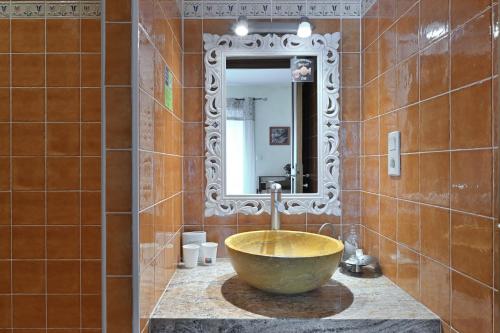 a bathroom with a bowl sink and a mirror at Les Hélianthèmes in Guchen