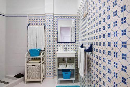 a bathroom with blue and white tiled walls and a sink at Casa Amarela in Tavira