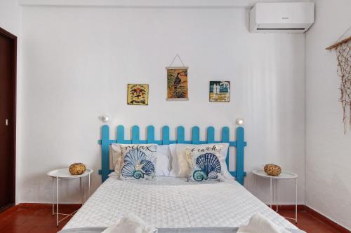 a blue bed in a white room with two tables at Casa Amarela in Tavira