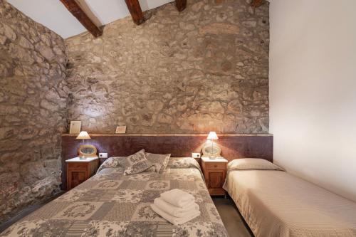 two beds in a room with stone walls at El Baluard De Ferreres in Olvan
