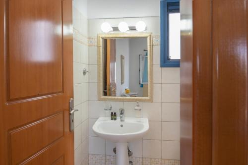 a bathroom with a sink and a mirror and a door at Studios Ninemia Serifos 1 in Livadi
