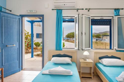 two beds in a room with blue doors and windows at Studios Ninemia Serifos 1 in Livadi