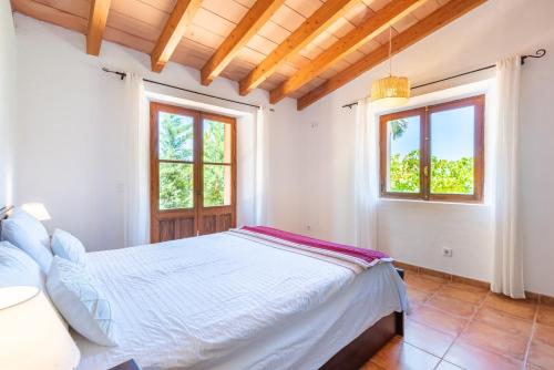 a white bedroom with a bed and two windows at Sa Teulera Soller in Sóller