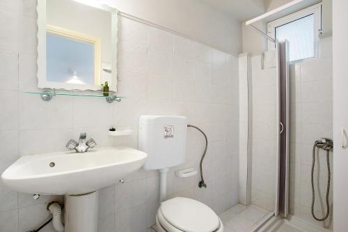 a white bathroom with a toilet and a sink at Dolphin Studio Sea View 10 in Keri