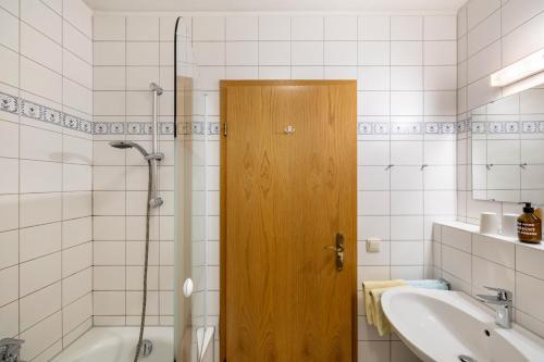 a bathroom with a wooden door and a tub and a sink at Fewo Brünnstein - Zimmer 6 in Oberaudorf
