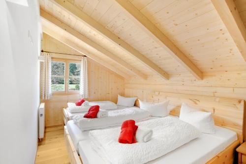 two beds in a log cabin with red pillows on them at Ferienwohnung Uferweg in Fischbachau