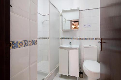 a white bathroom with a toilet and a sink at Vila Caracol in Guia