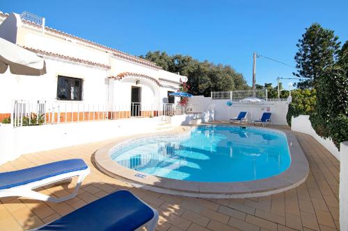 a swimming pool with chairs and a house at Vila Caracol in Guia