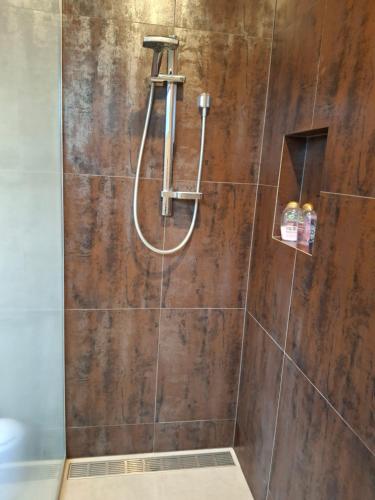 a bathroom with a shower with a wooden wall at Studio Hugoway Papamoa Beach Winter Special in Papamoa