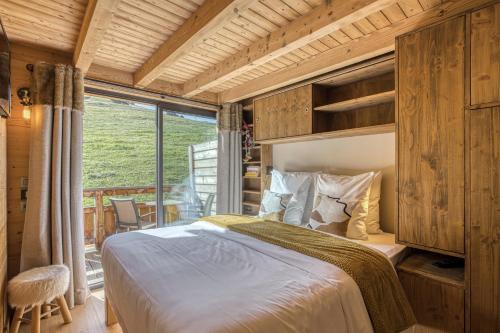 a bedroom with a bed and a large window at Chalet des joux in La Clusaz