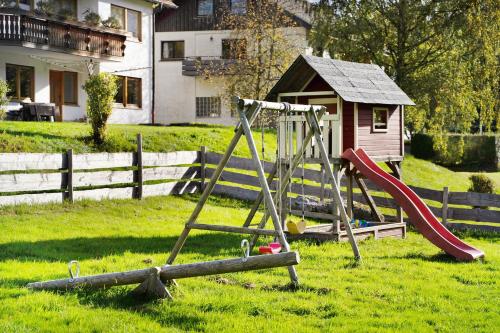 a playground in a yard with a slide and a house at Haus Löwen in Forbach