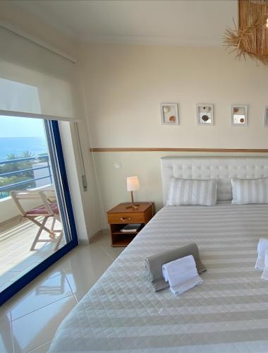 a white bedroom with a large bed and a window at Pérola do Atlântico By the Sea in Quarteira