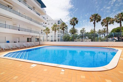 a swimming pool in the middle of a building with palm trees at Pérola do Atlântico By the Sea in Quarteira