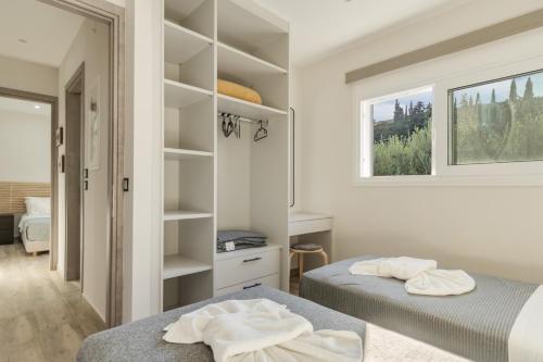 two beds in a white room with a window at Euphoria Apartments in Lixouri
