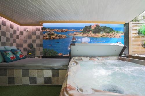 a room with a bath tub with a painting on the wall at Gîte Les Galets Blancs in Trébeurden