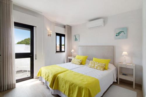 a bedroom with a bed with yellow sheets and a window at Casa Harlequin in Vale do Lobo