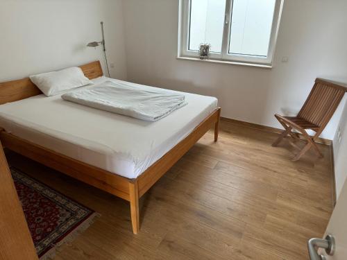 a bed in a room with a chair and a window at Hofberg Villa - Appartment in Landshut