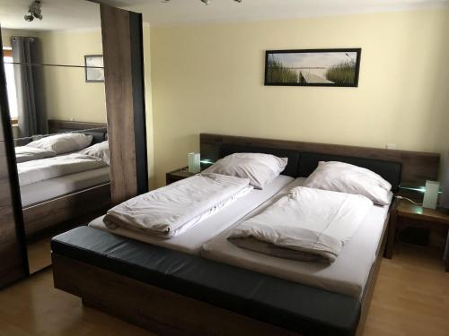 a bedroom with two beds with white sheets and a mirror at Ferienwohnung Wiesenblick in Plettenberg