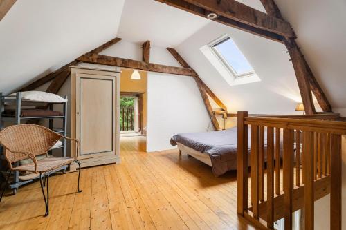 a attic bedroom with a bed and a chair at Gîte La Malcotais in Noyal-Châtillon-sur-Seich