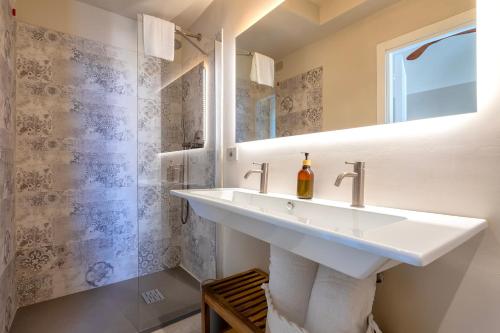 a white bathroom with a sink and a window at Dimora Sella - Casa Monica in Alghero